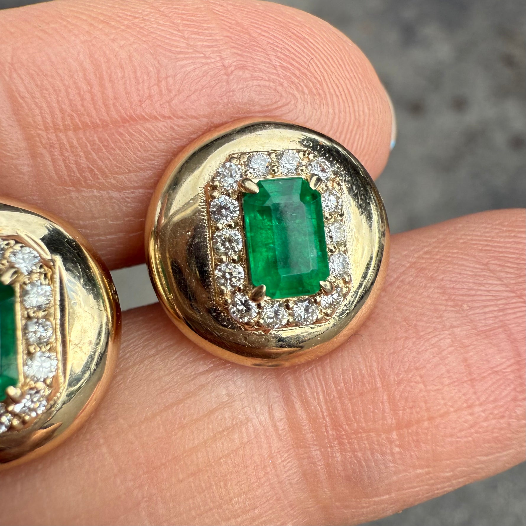 Close-up of emerald and diamond stud earrings in 14K yellow gold