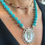 Mother of pearl pendant featuring La Caridad del Cobre on a turquoise interchangeable necklace. 