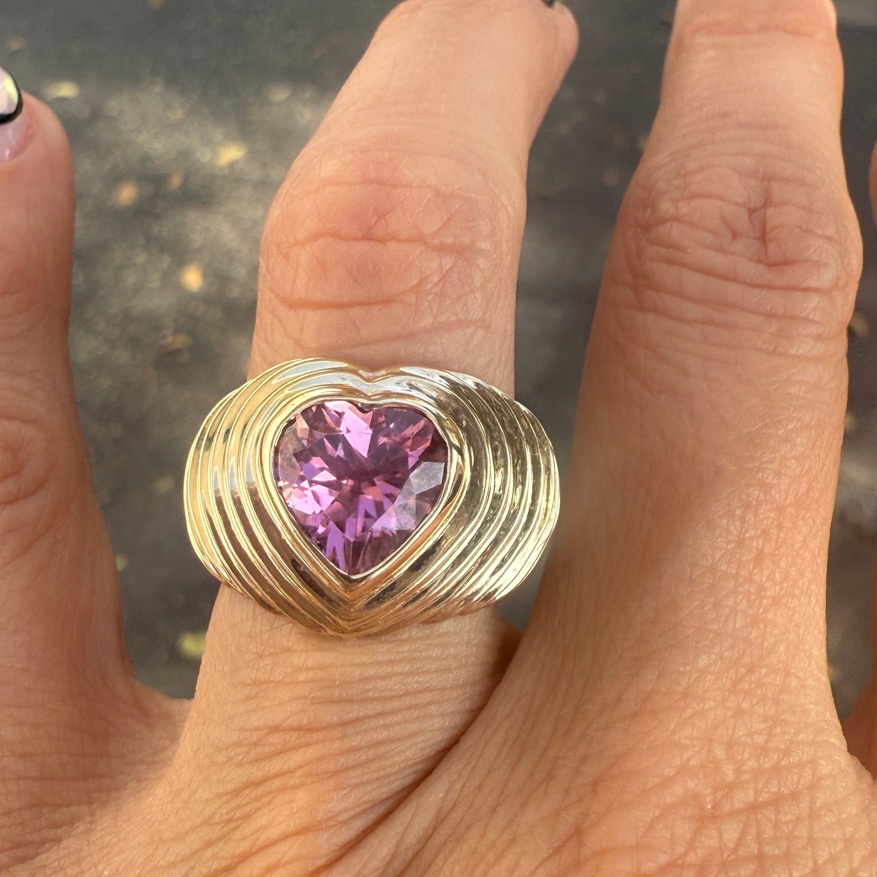 Heart shaped pink tourmaline mounted on a wide yellow gold band with stripe details. Designed by Miriam Santayana.