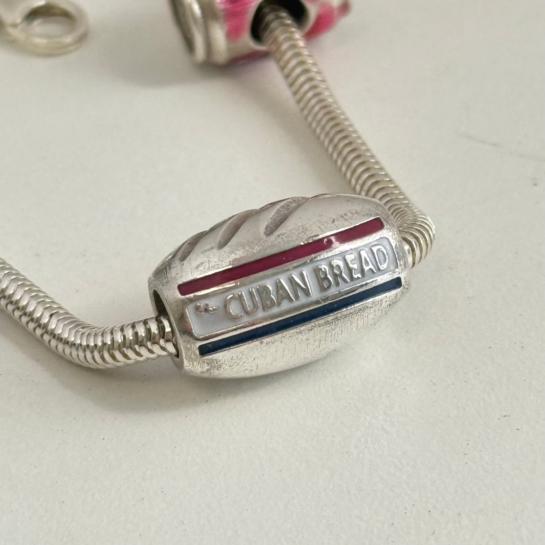 Silver charm shaped like a loaf of Cuban bread on a light background
