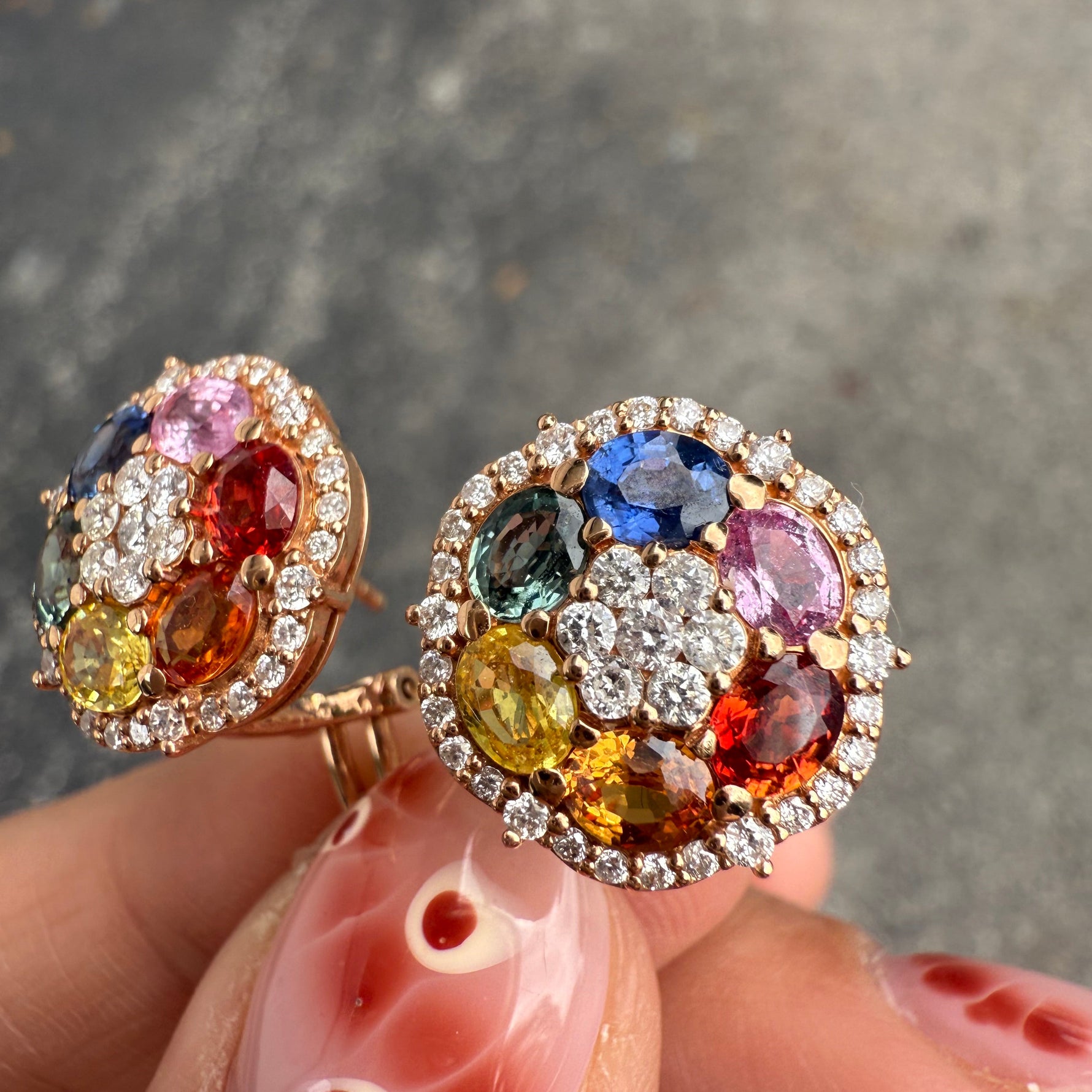 Close-up of rainbow sapphire earrings with diamond halo in rose gold