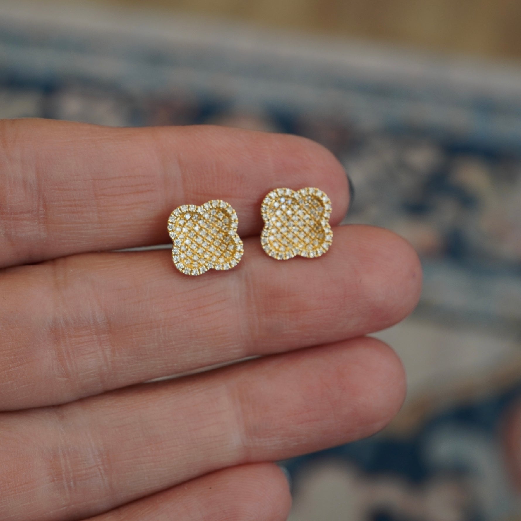 Clover shaped earrings with diamonds between fingers.