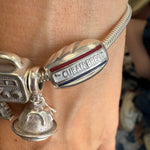 Silver bracelet with 'Cuban Bread' charm on a wrist.