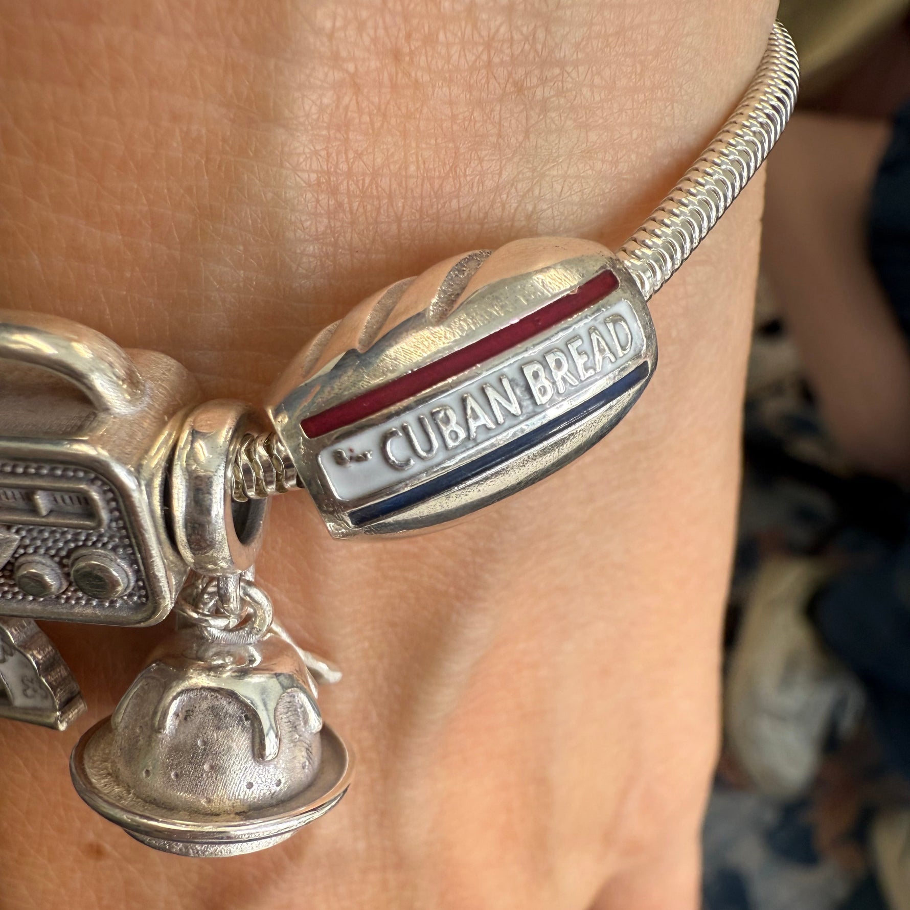 Silver bracelet with 'Cuban Bread' charm on a wrist.