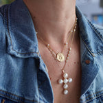 A gold cross with freshwater pearls designed by Santayana Jewelers