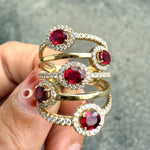 Close-up of oval ruby with diamond halo set in yellow gold ring