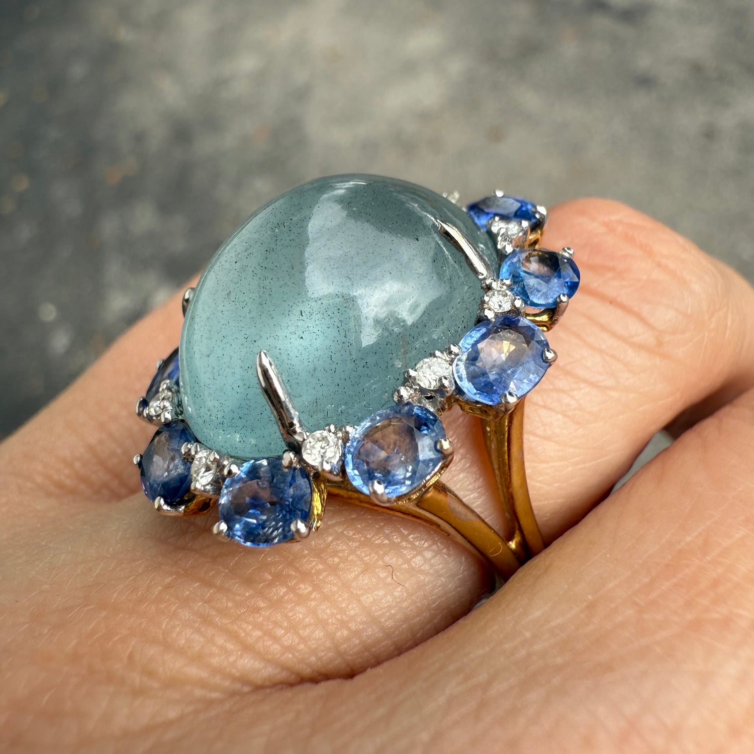 Side view of aquamarine, sapphire, and diamond cocktail ring in 14K gold