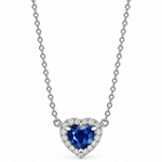 A heart-shaped pendant necklace featuring a deep blue heart-shaped sapphire surrounded by a halo of small diamonds, suspended on a white gold chain against a plain white background.