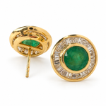 Round emerald and baguette diamond halo stud earrings in 14K yellow gold, 12.5 mm diameter, with push-back closures.