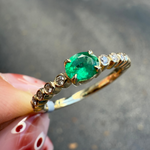 Dainty emerald and diamond ring in 14K yellow gold worn on hand, handcrafted by Santayana Jewelers Miami