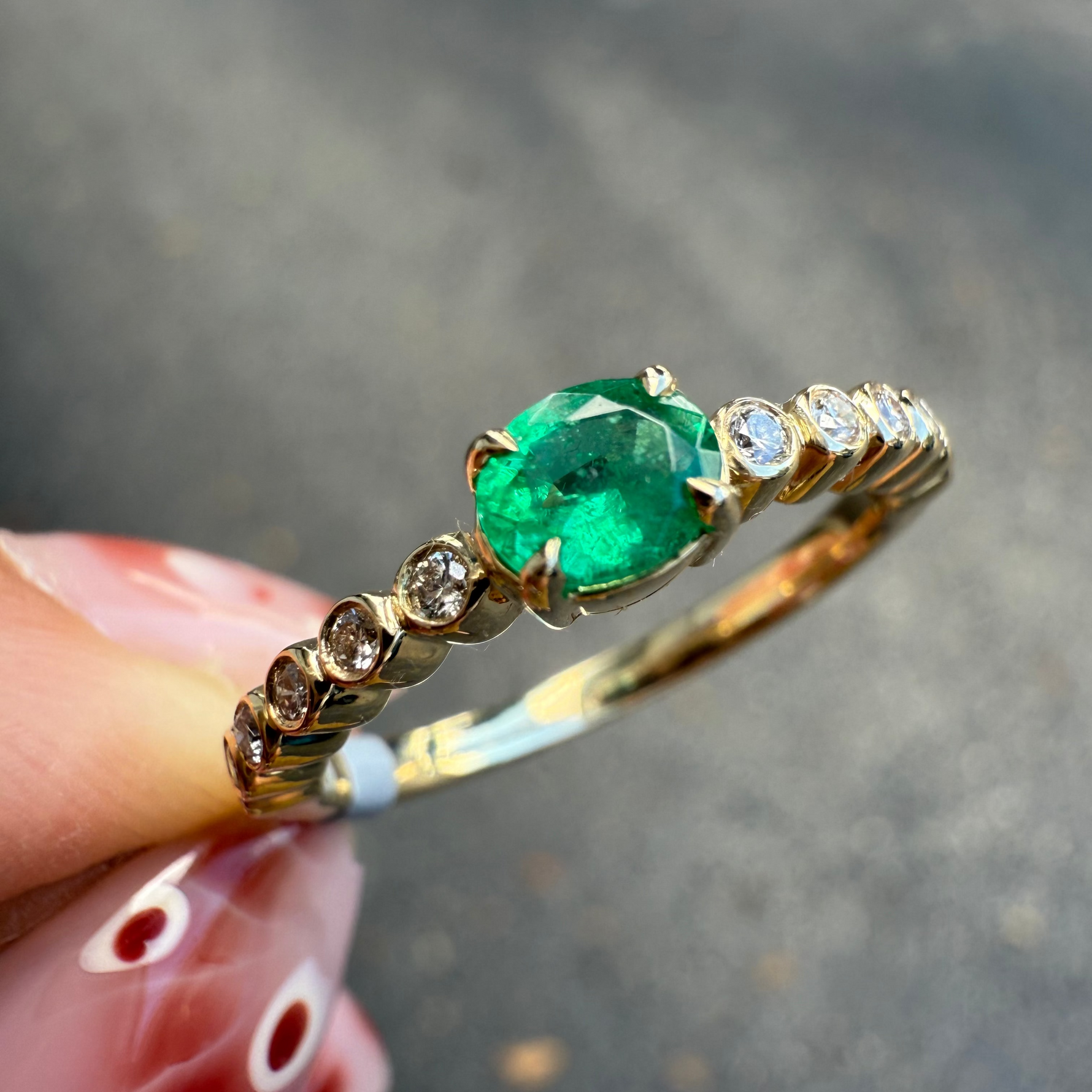 Dainty emerald and diamond ring in 14K yellow gold worn on hand, handcrafted by Santayana Jewelers Miami