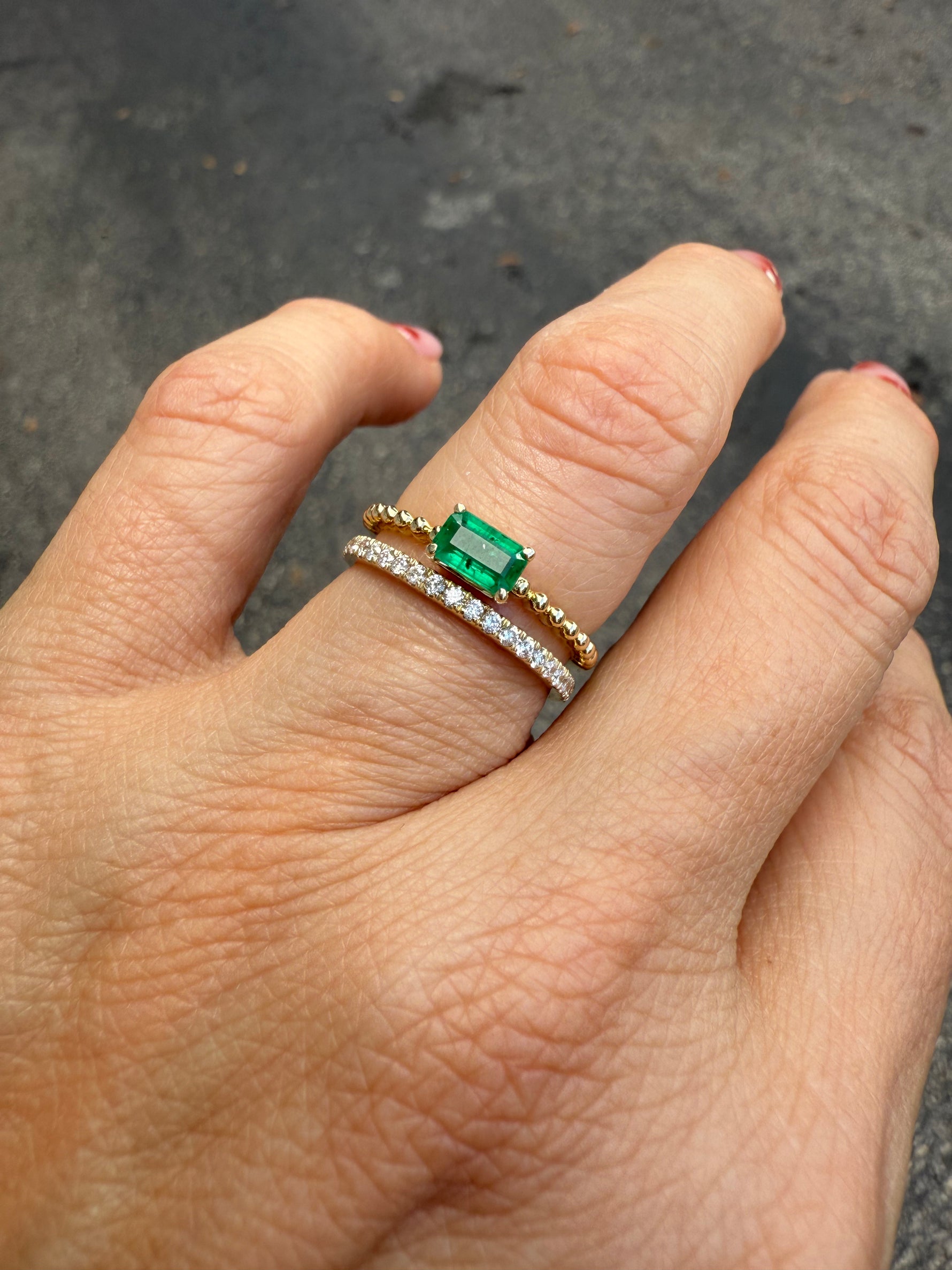 Emerald and diamond stacking ring in 14K yellow gold, two-in-one design on a finger