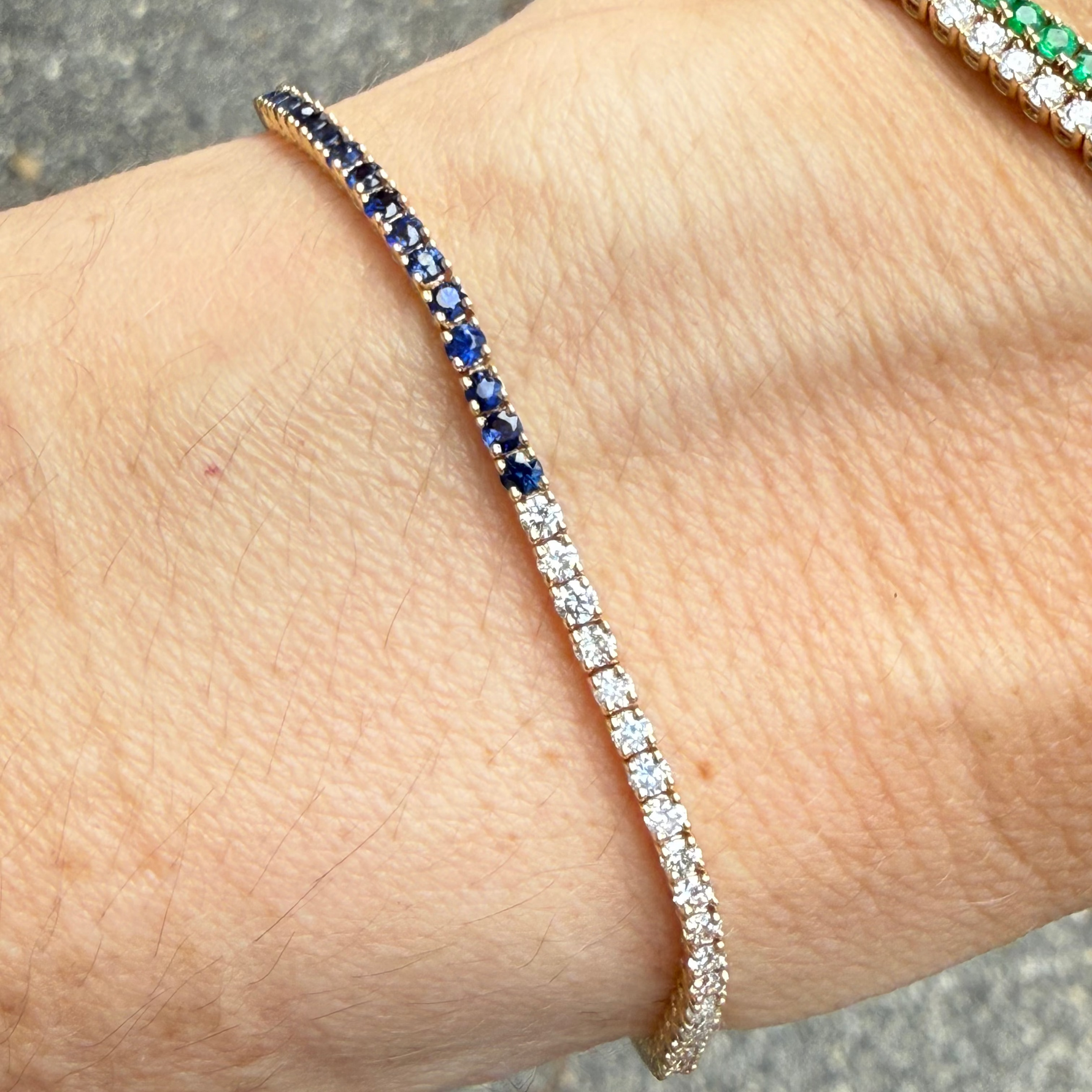 Sapphire and diamond half tennis bracelet in 14K gold on a wrist.