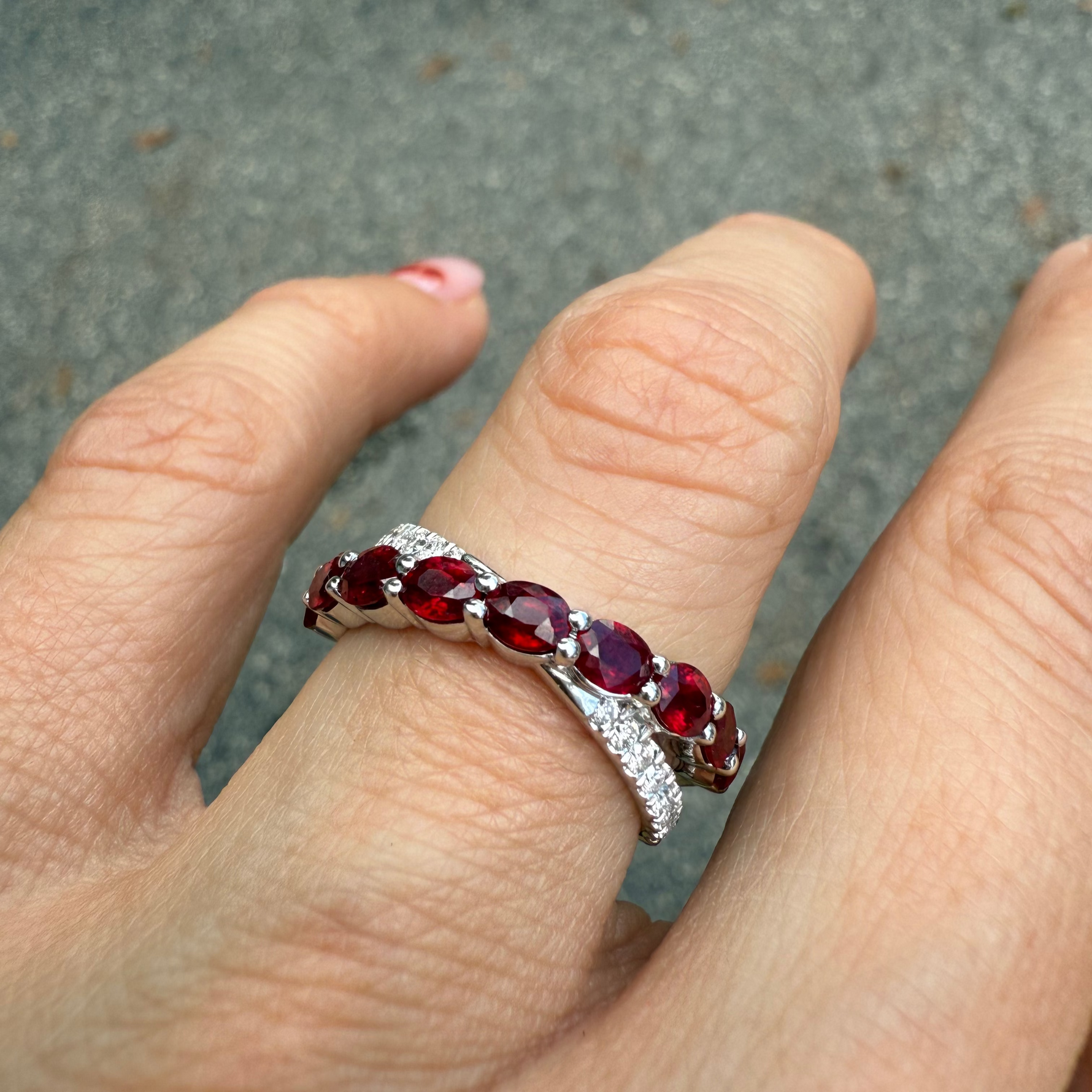 Ruby and diamond crossover band in 14K white gold, on a finger