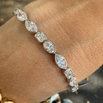 White gold bezel set multi shape lab created diamond tennis bracelet on wrist. 