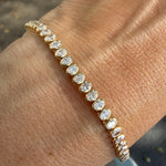 Yellow gold bezel set tennis bracelet with lab created oval diamonds. 