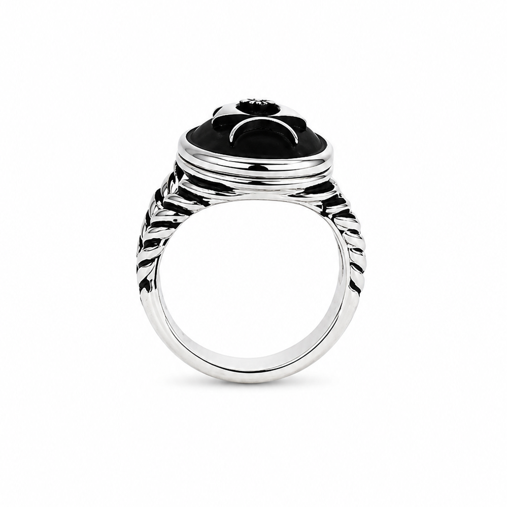 A silver-toned ring featuring a black onyx cabochon with a stylized black-and-white face design, set against a plain white background.