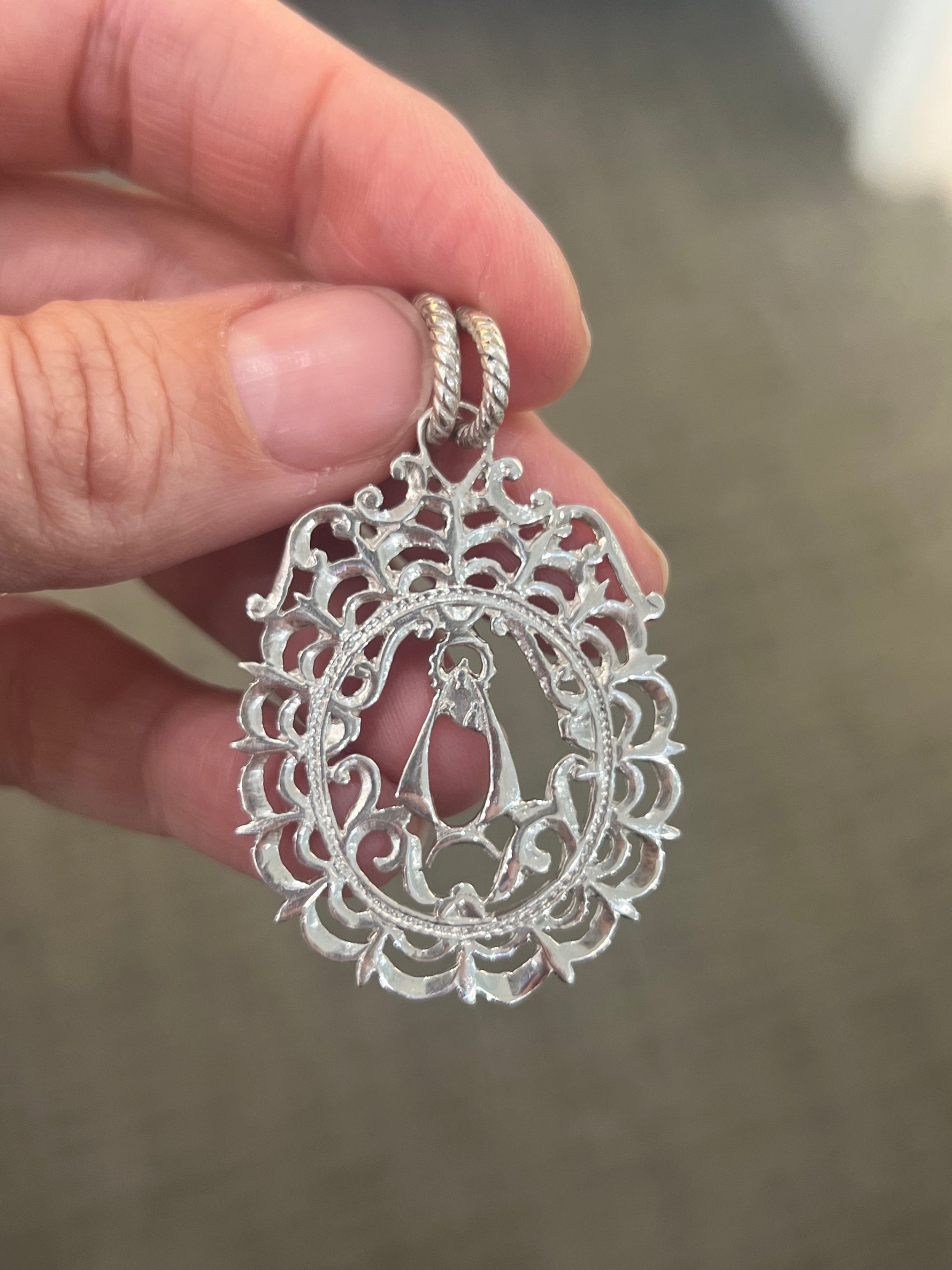 Close up of silver virgencita pendant.
