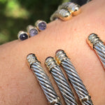 Closeup of 14k and sterling silver twist bangles on a person's arm
