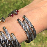 A collection of 14K and sterling silver twist bangles with red stones