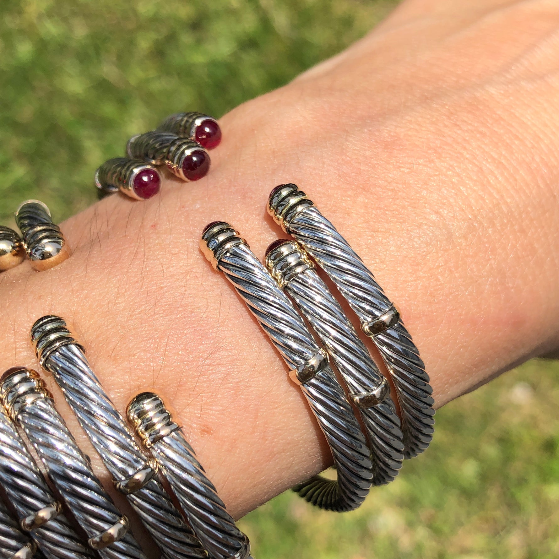 A collection of 14K and sterling silver twist bangles with red stones