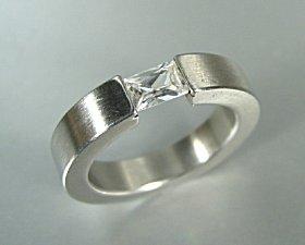 Emerald-cut diamond in tension ring.